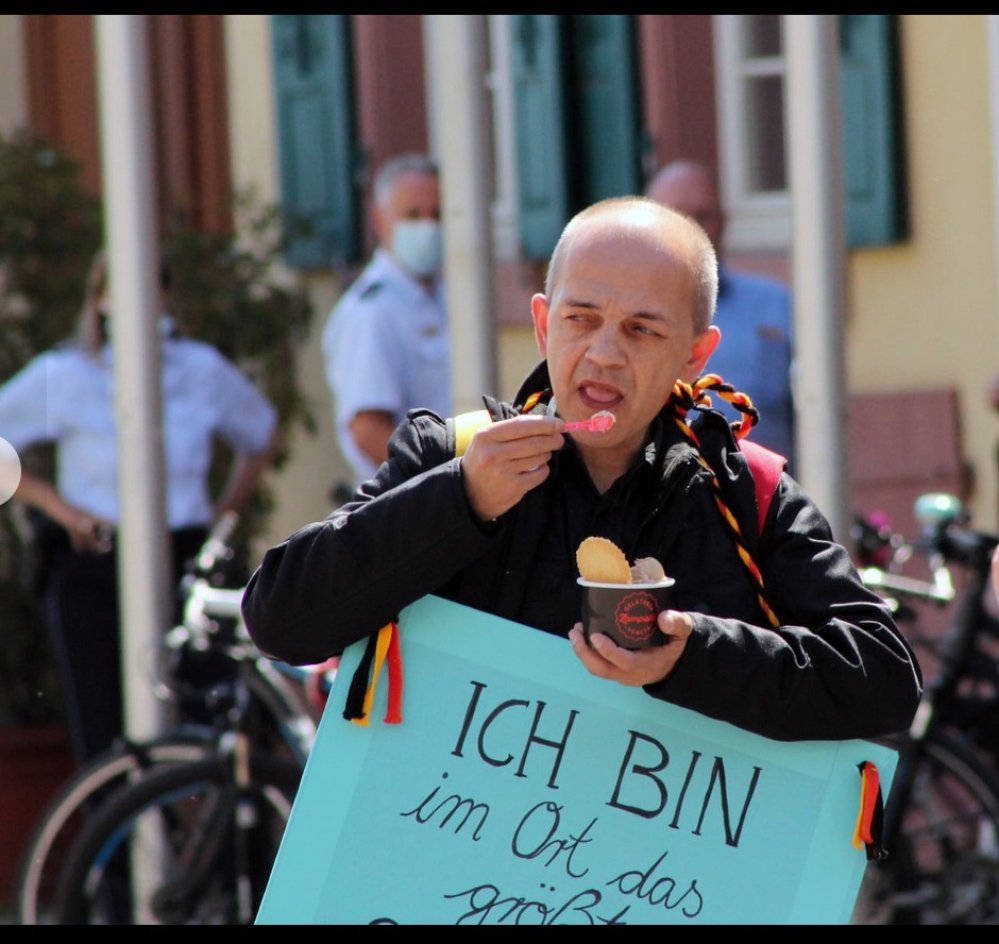 Der Offenburger Stadtratsabgeordnete und Landtagskandidadat Taras Maygutiak lief am 16. Mai 2020 bei einer "Corona-Demonstration" mit einem Schild um den Hals mit der Aufschirft: Ich bin im Ort das größte Schwein und trete für die Grundrechte ein". 