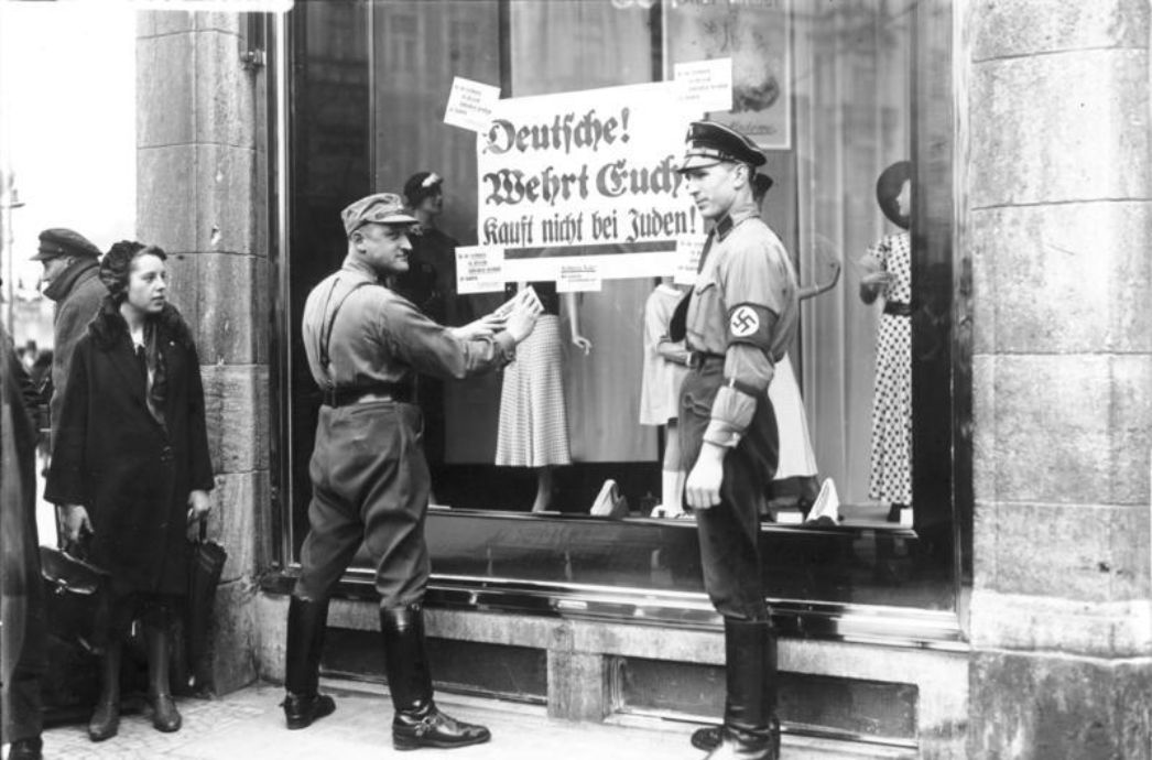 SA-Männer bringen in Berlin im Jahr 1933 antisemitische Plakate an, die zum Boykott jüdischer Geschäfte aufrufen.