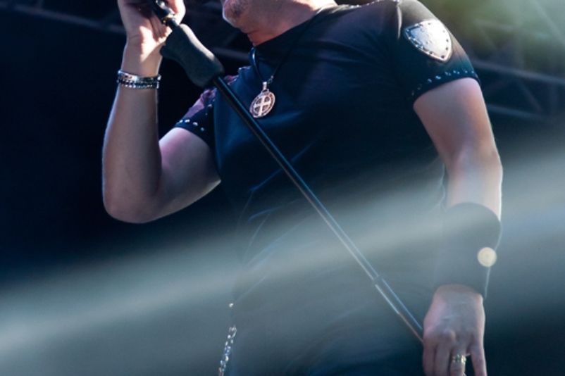 Marko Perković (Thompson) mit Mikrofon bei einem Konzert, August 2013, im schwarzen Hemd vor dunklem Bühnenhintergrund.